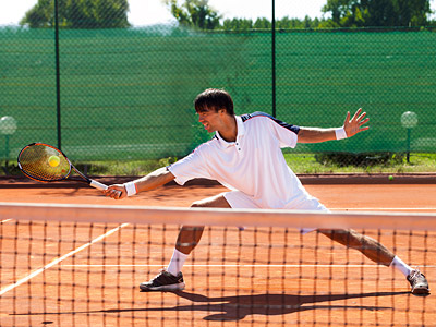 Ein Tennisspieler schlägt einen Ball auf einem Sandplatz.